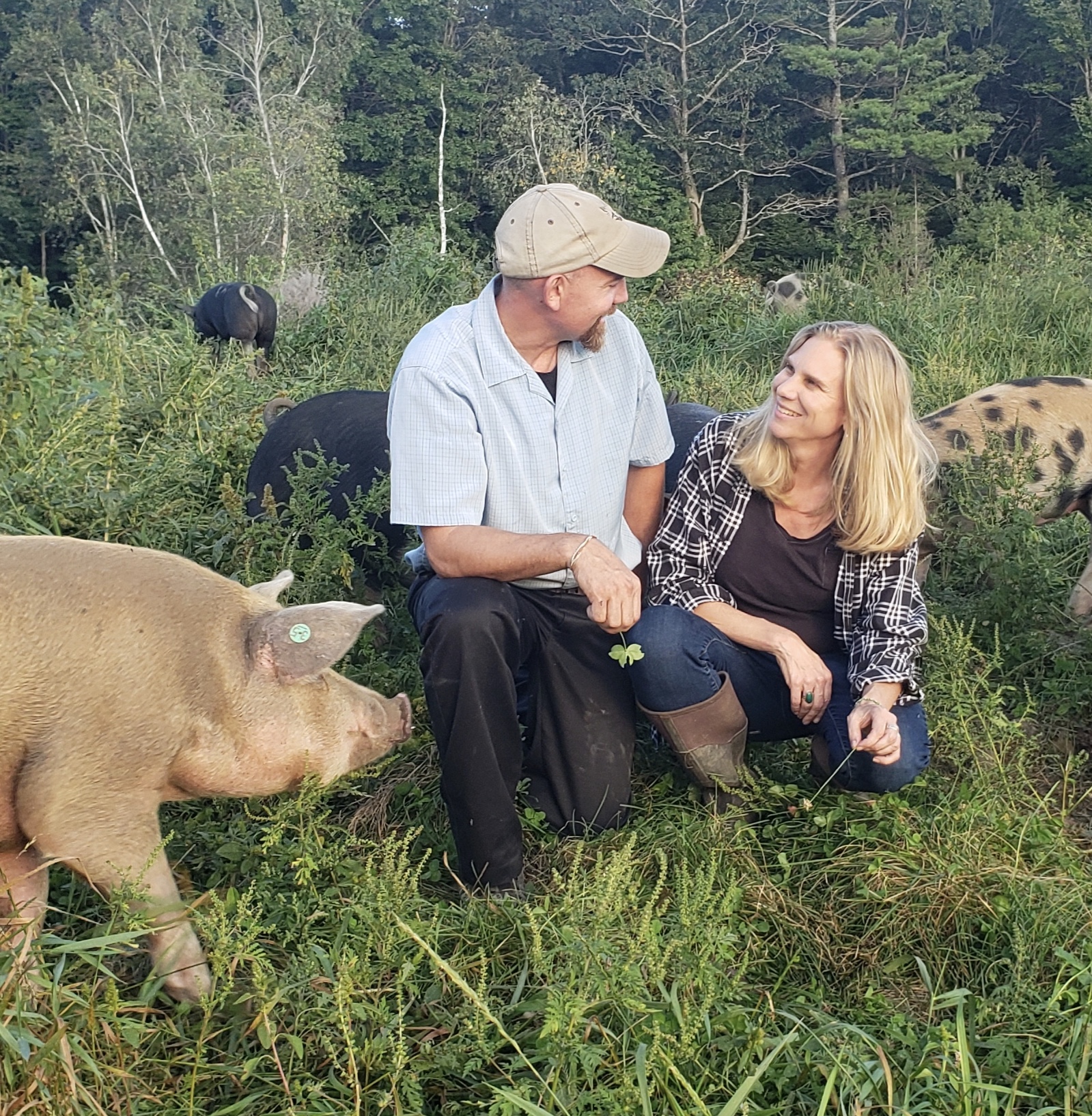 John and Holly Arbuckle in field with Singing Pastures pigs