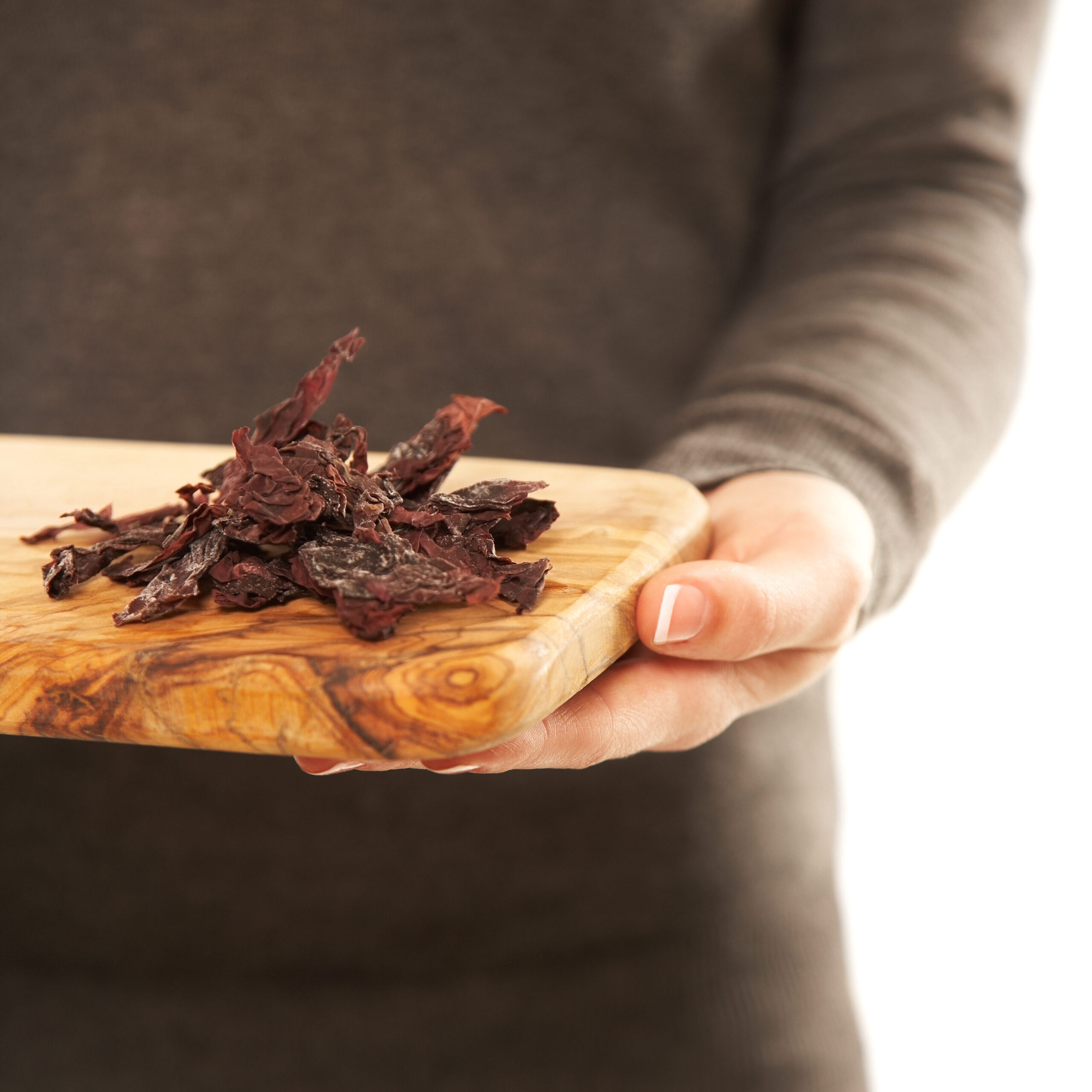 Mid Section of young woman holding  a wooden cutting board with dried dulse seaweed