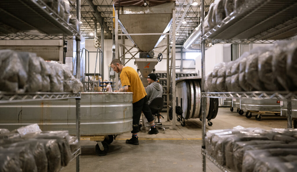 Workers in facility through shelves of grow bag packaging