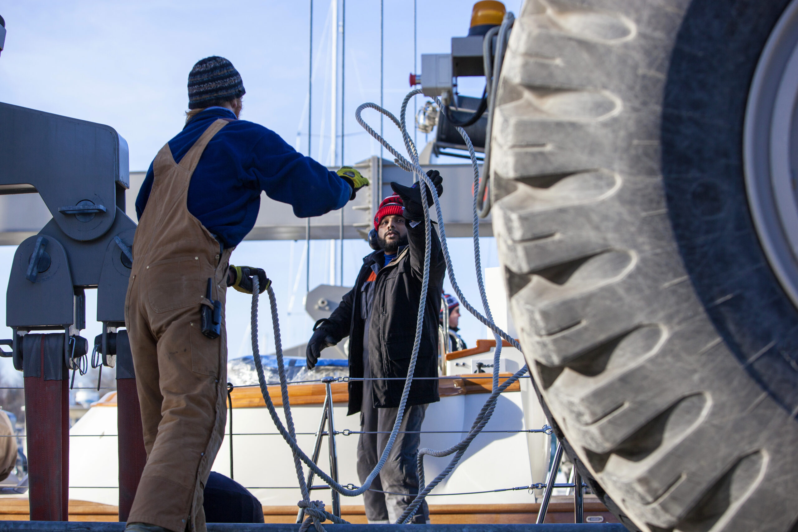 Two Front Street Shipyard workers tossing rope across docking port